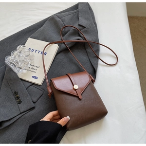 Detail of contrast stitching and lychee grain leather on a mini crossbody phone bag