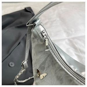 Detail of silver metallic hobo bag with butterfly hardware and decorative chain strap