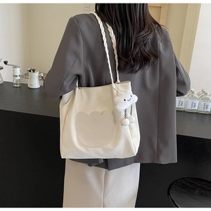 Détail du cabas en toile crème avec bandoulière tissée et accessoire de charme nuage