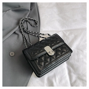 Detail of black quilted leather shoulder bag featuring silver chain strap and metal lock