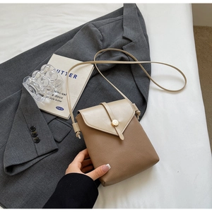Detail of two-tone crossbody bag with brown lychee texture and gold buckle hardware