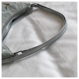 Detailed close-up of silver tote bag with metallic butterfly buckle and chain strap
