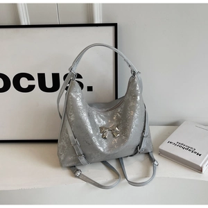 Dettaglio della borsa argento metallizzato con texture crackle e fiocco in metallo