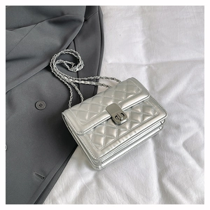 Detailed view of silver quilted crossbody bag with metal chain strap and push-lock closure