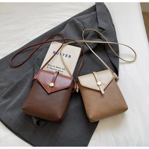 Detail of mini leather crossbody bags in brown and khaki with V-cut flap on blazer