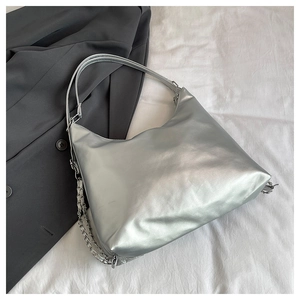 Detail of silver matte hobo bag featuring decorative metal chain on white fabric