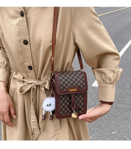 Détail d'un sac de téléphone en cuir marron vintage avec motif géométrique et breloque