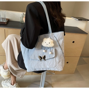 Close-up of light blue nylon tote bag with butterfly buckle and plush cloud charm