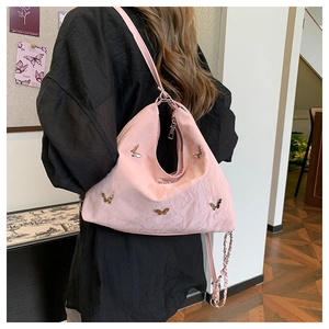 Pink satin hobo bag with silver butterfly charms and chain strap shown on model