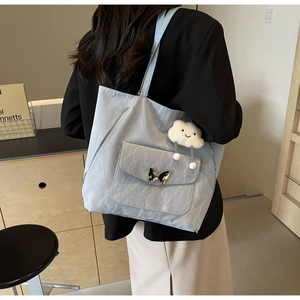 Detail of light blue tote bag featuring crinkled texture and metal butterfly buckle clasp