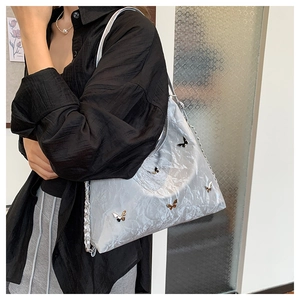Close-up of a silver tote bag with metallic butterfly accents and pleated texture