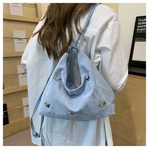 Back view of a light blue large capacity tote bag with silver butterfly charms on strap