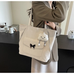 Close-up of beige tote bag with silver butterfly buckle and cloud plush charm detail