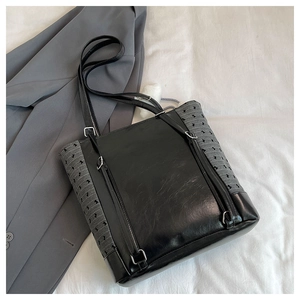Detail view of black glossy tote bag with grey diamond texture and long shoulder straps