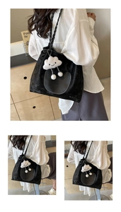 Détail du sac cabas noir avec pendentif peluche et bandoulière tressée sur mannequin
