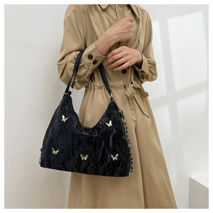 Close-up of black pleated leather tote bag with silver butterfly buckles and chain