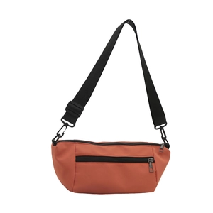 Minimalist brick red nylon crossbody bag with adjustable black strap and front zipper