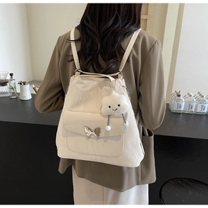 Close-up of a white tote bag with a silver butterfly buckle and a plush cloud charm