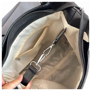 Detail view of the black tote bag showing silver metal hooks and interior zipper pocket