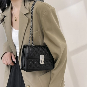 Chic black quilted crossbody bag with silver chain strap worn by model on shoulder