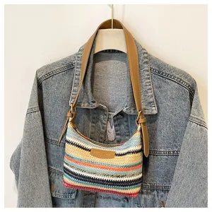 Detail of colorful woven stripe shoulder bag with brown leather strap and brand label
