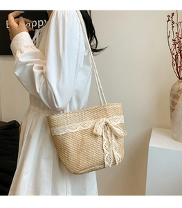 Detail of hand-woven straw tote bag with elegant lace trim and large decorative bow knot