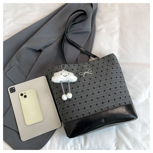 Detailed shot of a knit tote bag with cloud charm and silver bow on white fabric
