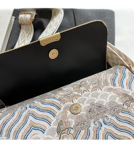 Close-up of wavy jacquard fabric handbag with gold magnetic closure and wide strap