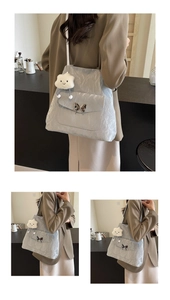 Detail of silver-grey tote bag with metallic butterfly buckle and plush cloud charm