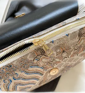 Macro detail of Chinese style embroidery texture and golden zipper on crossbody bag