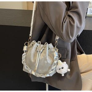 Silver drawstring bucket bag with metallic texture, gold hardware and plush charm