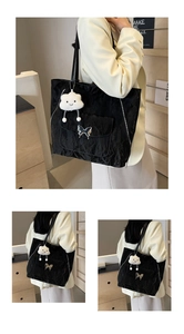 Large black tote bag featuring textured fabric, butterfly buckle pocket, and cloud charm