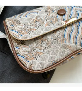 Detail of vintage landscape jacquard fabric and brown leather piping on crossbody bag