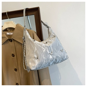 Detailed shot of silver pleated underarm bag with butterfly accents and metallic chain