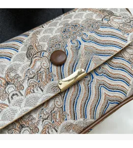 Detail of embroidered Great Wave pattern on stylish crossbody bag with gold metal buckle