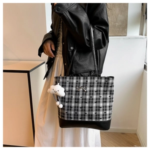Close-up of checkered tote bag with metal bow detail and white plush cloud charm