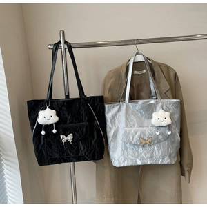 Detail of trendy tote bags with pleated texture, silver finish and metallic butterfly charm