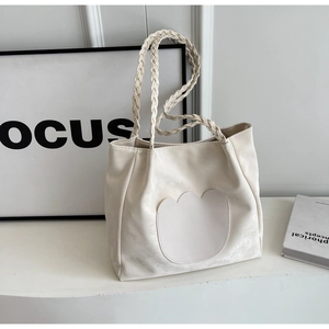 Détail du sac fourre-tout blanc cassé avec appliqué floral et bandoulière tressée