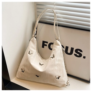 Detail of off-white tote bag with silver butterfly charms and elegant chain straps