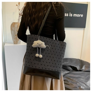 Detail view of large tote bag with grey texture and plush charm on female model