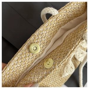 Detail of straw woven bag showing magnetic gold clasp closure and white lace trim edge