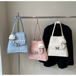 Detailed view of tote bags in light blue, pink and off-white with butterfly buckles