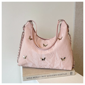 Detail of pink pleated tote bag featuring silver butterfly charms and chain strap