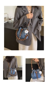 Detail of blue denim bucket bag with brown leather braided handle and plush ball charm