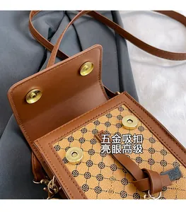 Détail d'un petit sac bandoulière marron avec boucles magnétiques et motifs trèfles noirs