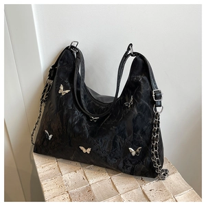 Detail of black wrinkled hobo bag with silver butterfly charms and dual chain straps