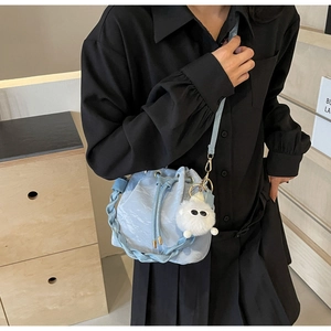 Dettaglio borsa a secchiello intrecciata azzurra con coulisse e ciondolo in peluche bianco