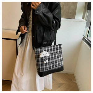 Detail of plaid tote bag with black bow embroidery and plush cloud keychain