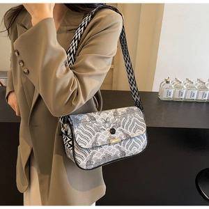 Close-up of wavy pattern crossbody bag with a wide geometric strap and metallic handle