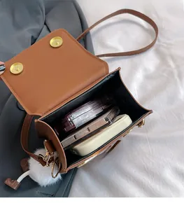 Capacité interne du sac bandoulière en similicuir marron montrant maquillage et mobile